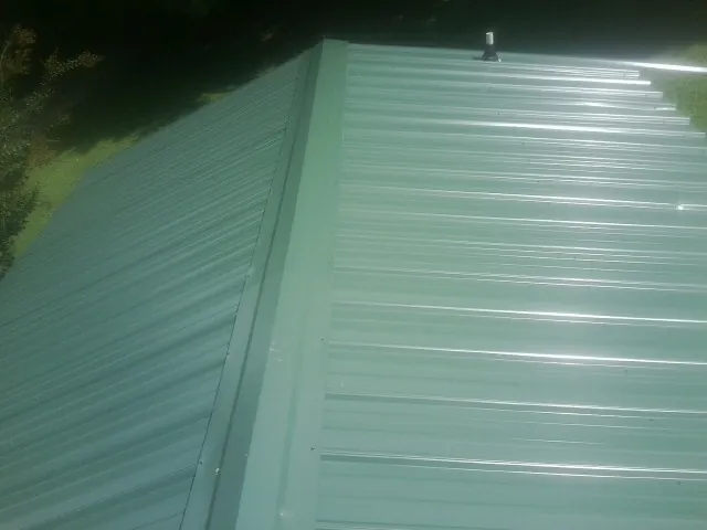 New green metal panels meeting at the ridge of a roof — Flat Roof Repair work by our crew in Payson
